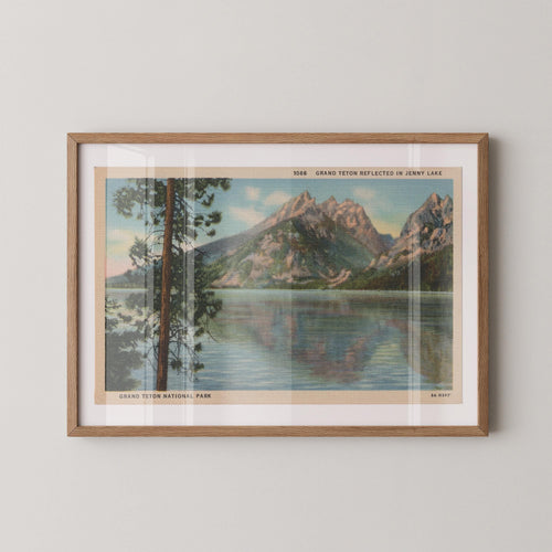 Vintage landscape postcard print of Jenny Lake with the jagged snow-capped peaks of the Grand Tetons reflected in the still water, Grand Teton National Park. Printed as a giclée fine art print on archival matte paper.